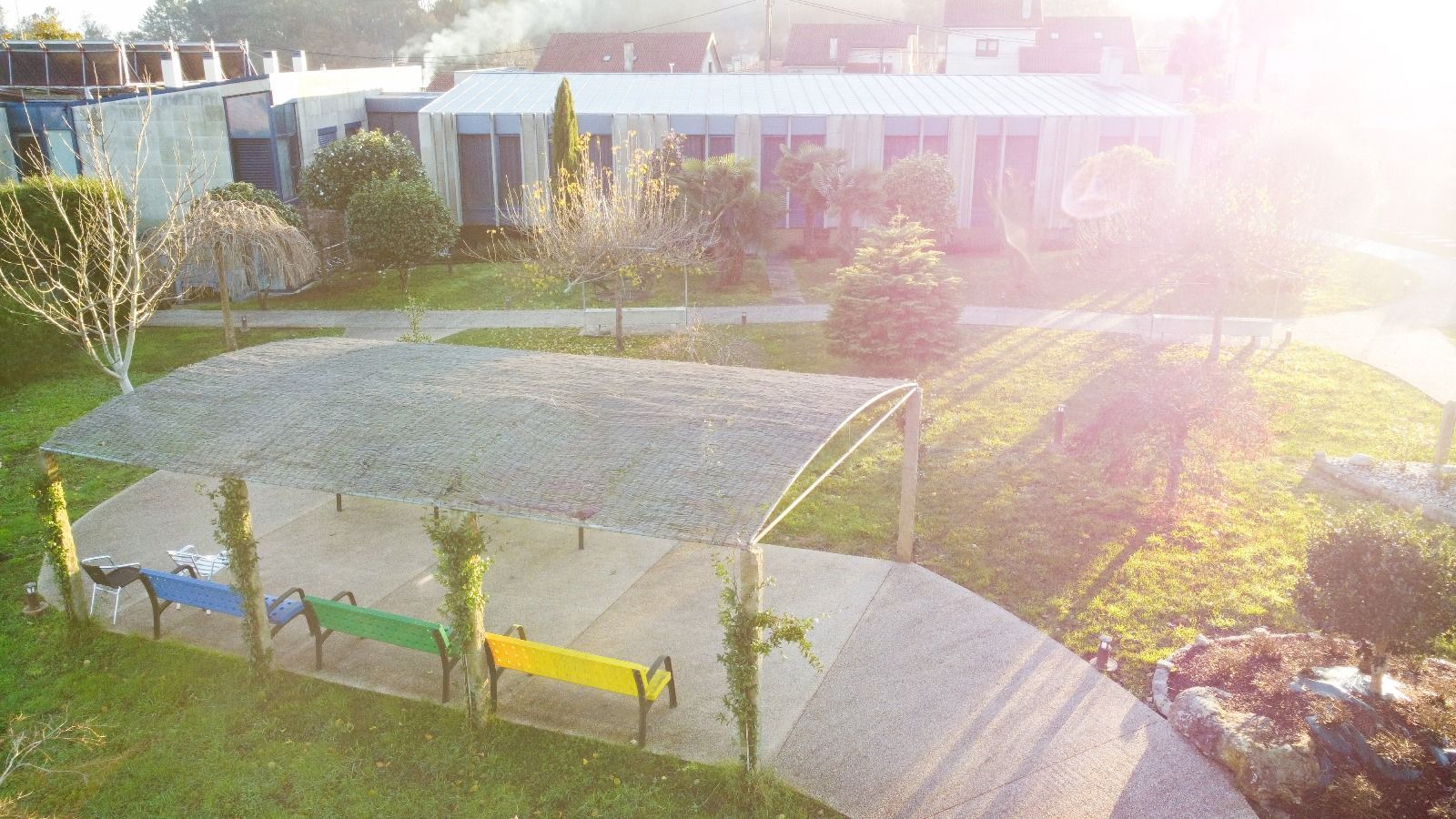 Una fila de bancos coloridos en un parque con un edificio al fondo.