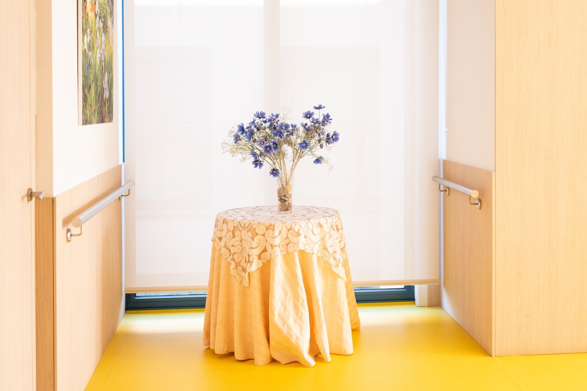 Una mesa con un jarrón de flores encima en un pasillo.