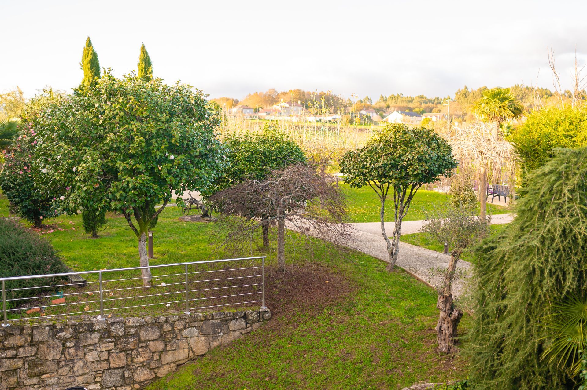 Una vista de un parque con árboles y un muro de piedra.