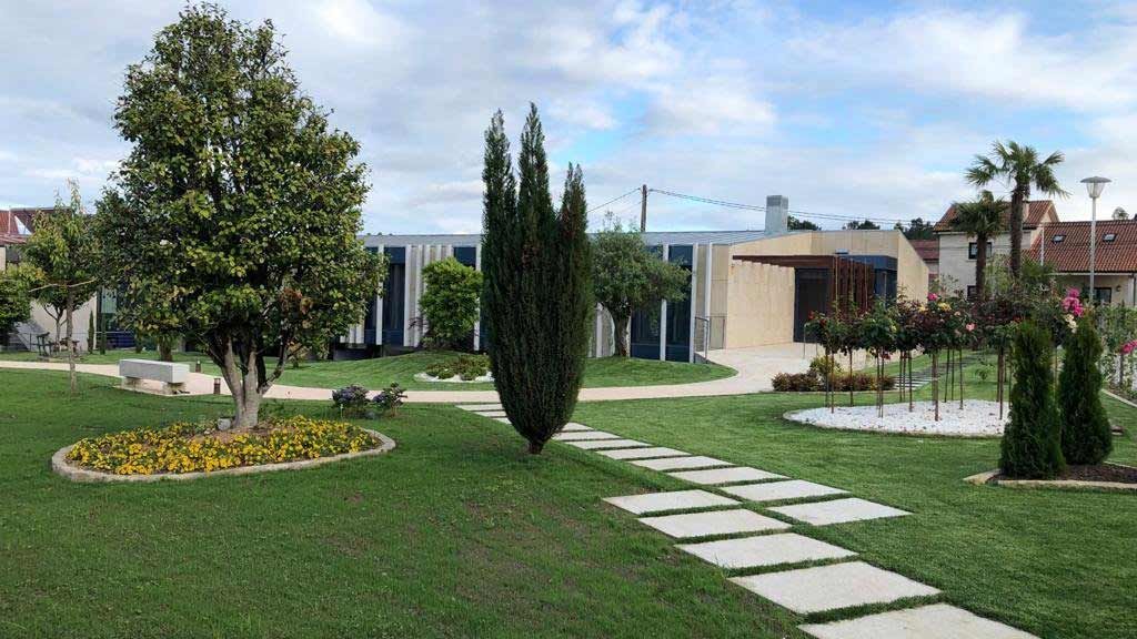 Un exuberante parque verde con árboles y un camino que conduce a un edificio.