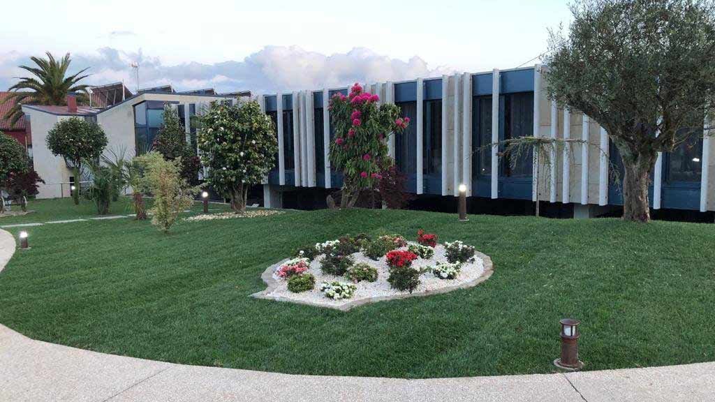 Un gran edificio con un jardín circular delante.