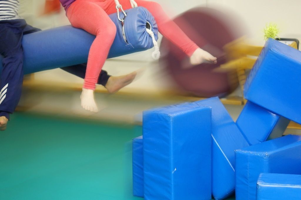 Henkilö tasapainoilee keinussa ja potkii pehmopalikoita nurin; Activus Oy:n terapiaympäristö