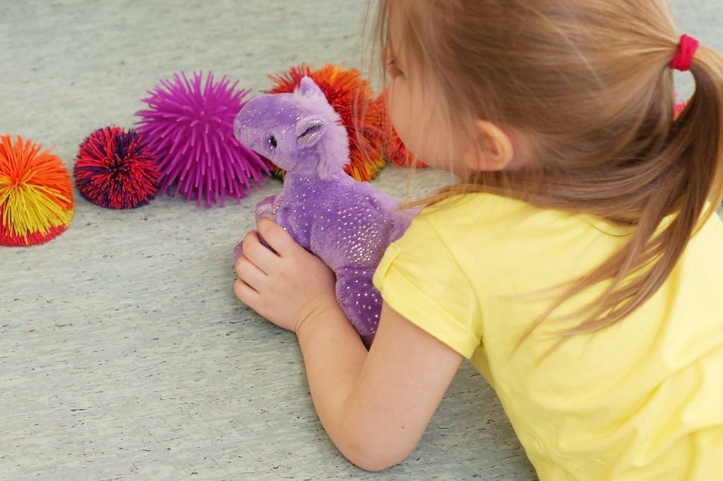 Lapsi makaa vatsallaan lattialla ja järjestelee leluja; Activus Oy:n terapiaympäristö