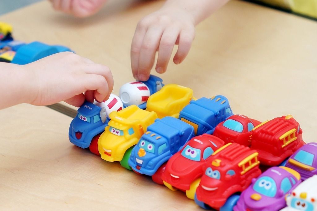 Lapsen käsi laittaa värikkäitä leluautoja riviin; Activus Oy:n terapiaympäristö