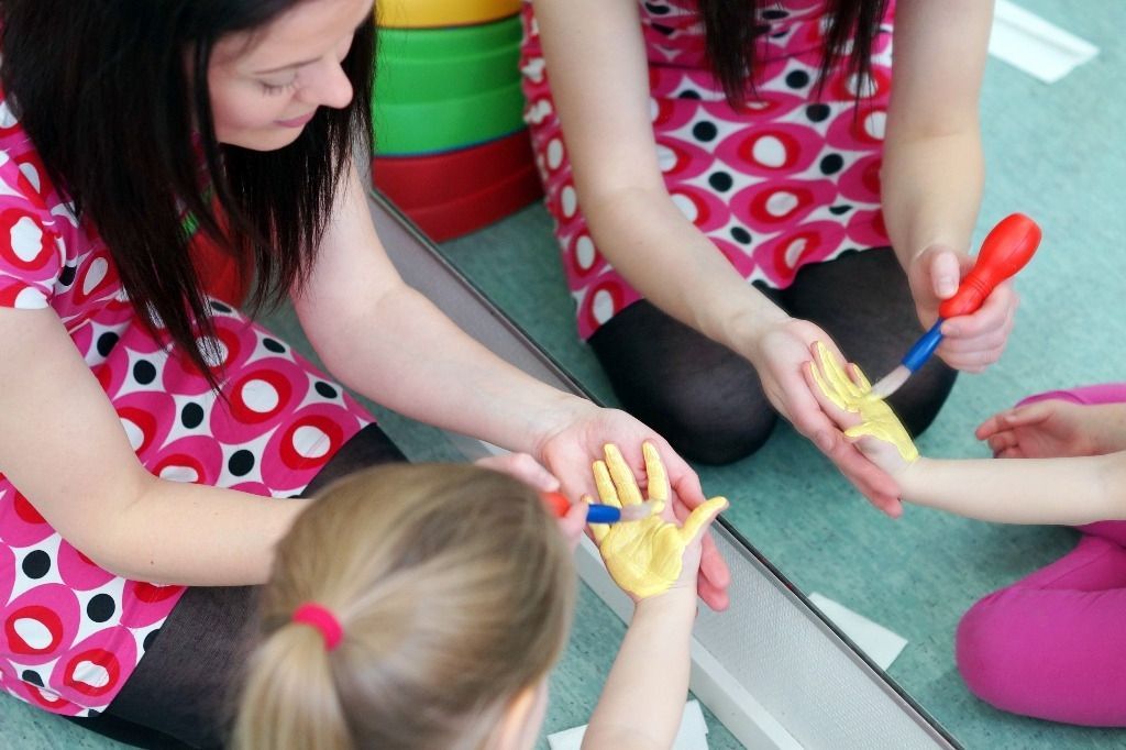 Terapeutti maalaa lapsen kättä keltaiseksi; Activus Oy:n terapiaympäristö