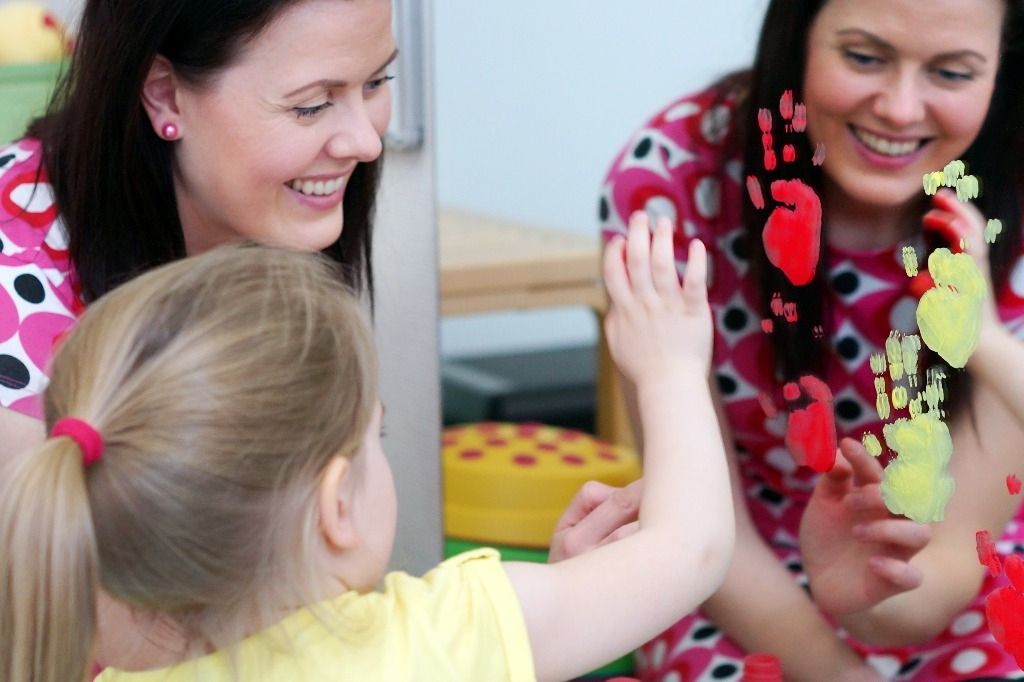 Terapeutti ja lapsi hymyilevät toisilleen leikkien lomassa; Activus Oy:n terapiaympäristö