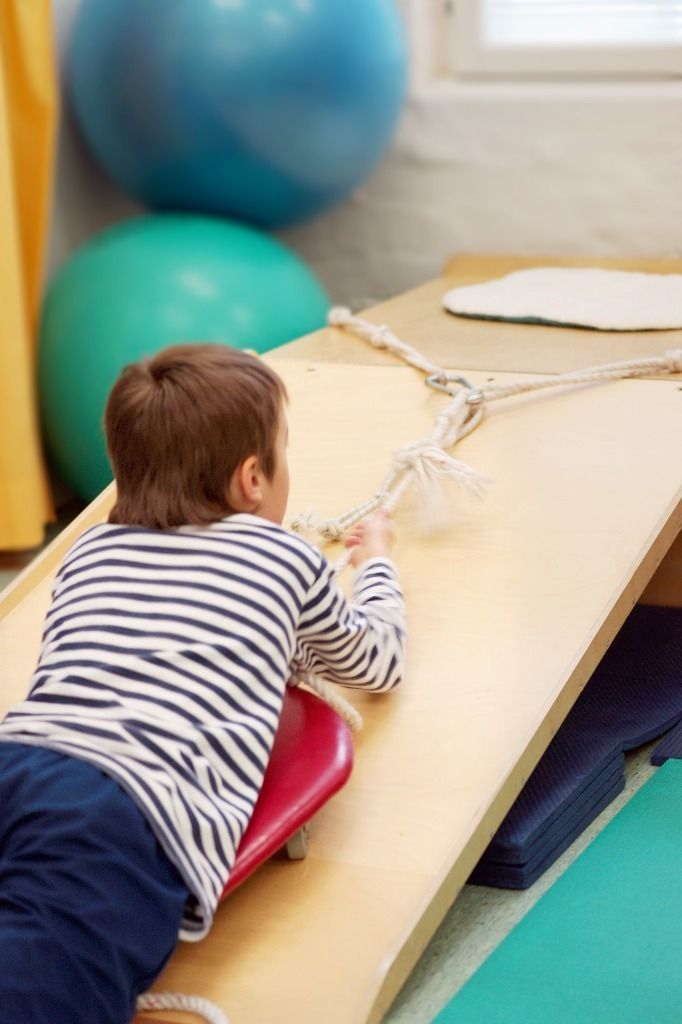 Lapsi vetää itsensä käsivoimilla ylös liukumäkeä; Activus Oy:n terapiaympäristö