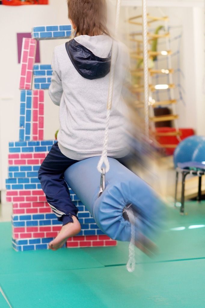 Lapsi sinisessä keinussa törmäämässä pahvisiin palikoihin; Activus Oy:n terapiaympäristö