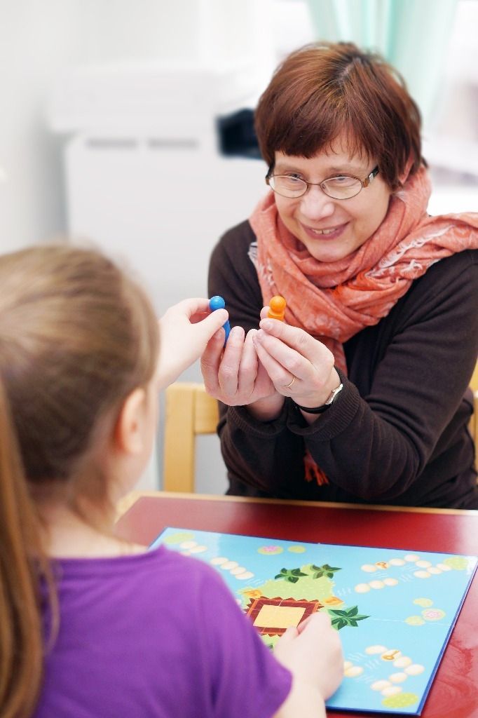 Lapsi pelaa lautapeliä terapeutin kanssa; Activus Oy:n terapiaympäristö