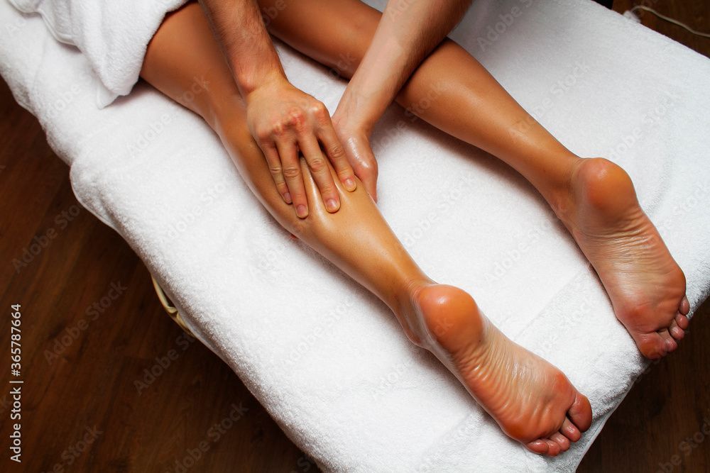 Zwei Beine und Füsse werden mit Lotion eingecremt und auf einer Spa-Behandlungsliege massiert.