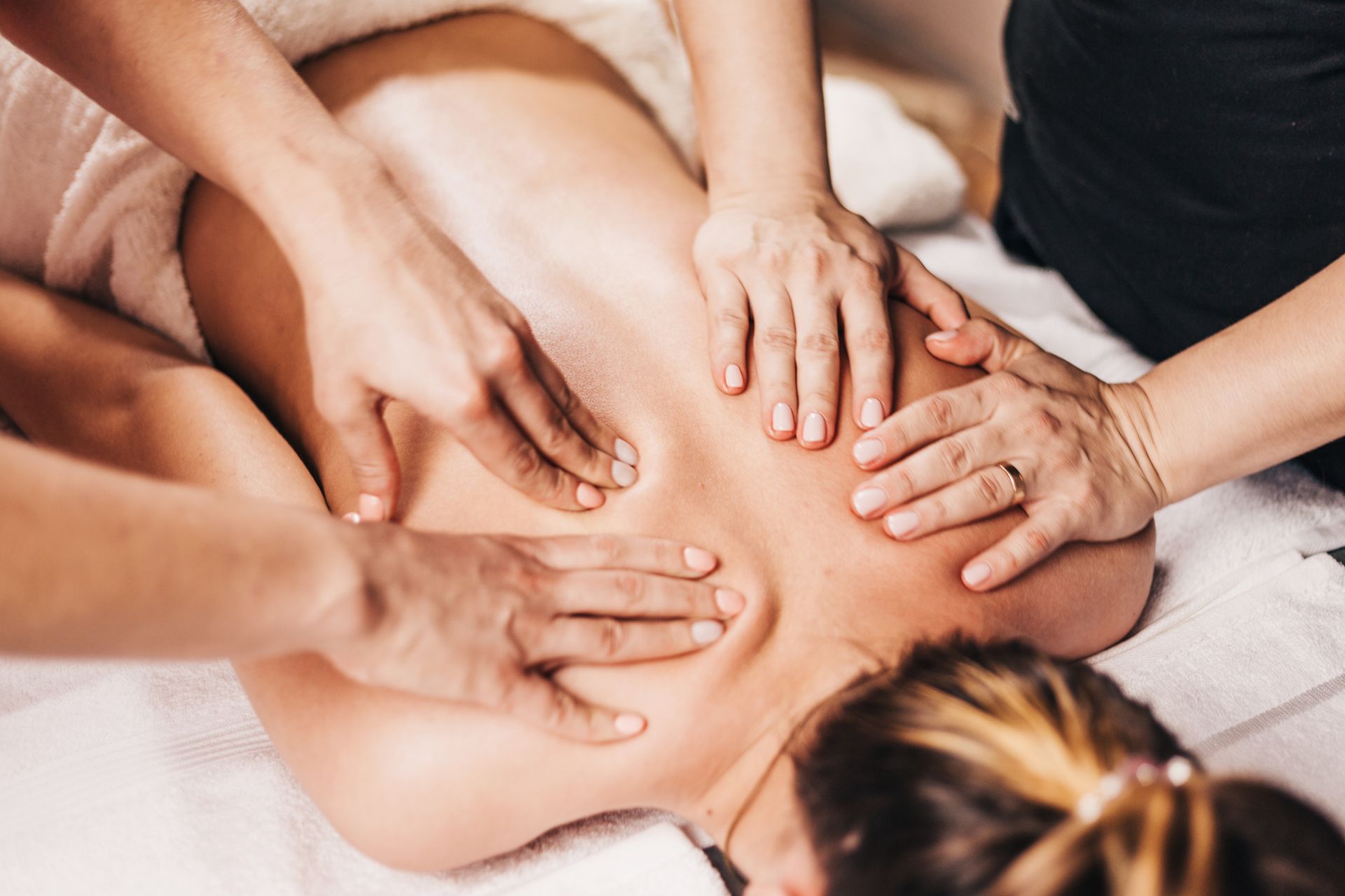 Die Hände liegen während einer Gruppenmassage oder Therapiesitzung auf dem nackten Rücken einer Person.