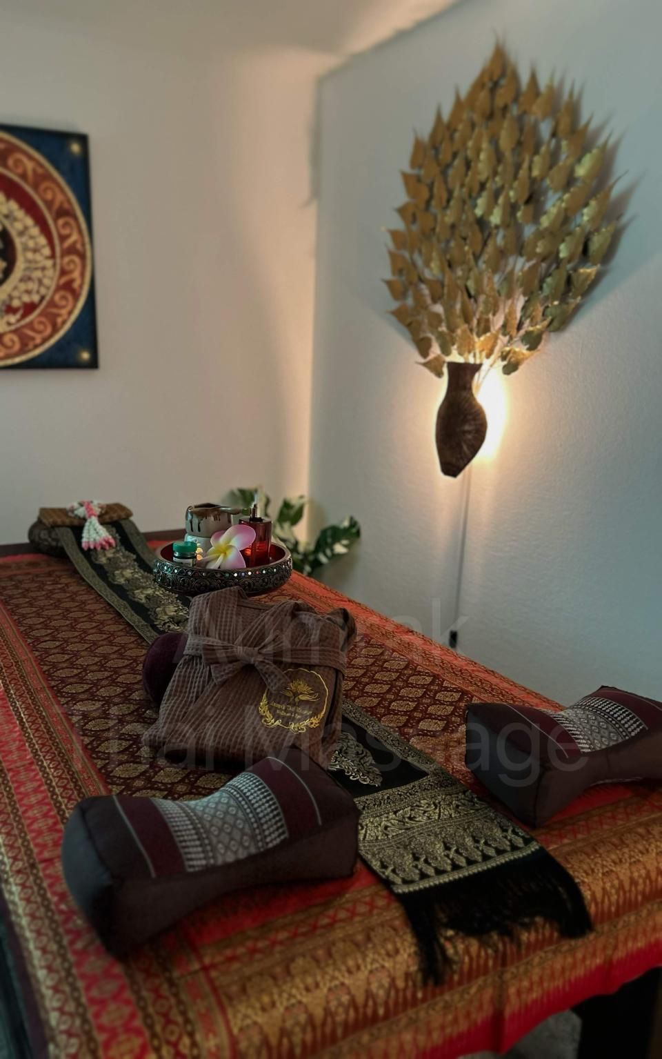 Dekorativer Esstisch mit gemustertem Tischläufer, Kerzen, Blumen und Wandbildern mit Blättern in einem warm beleuchteten Raum