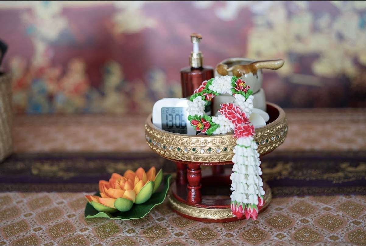 Verziertes Puja-Tablett mit Blumen, Süssigkeiten und rituellen Gegenständen auf einer gemusterten Oberfläche