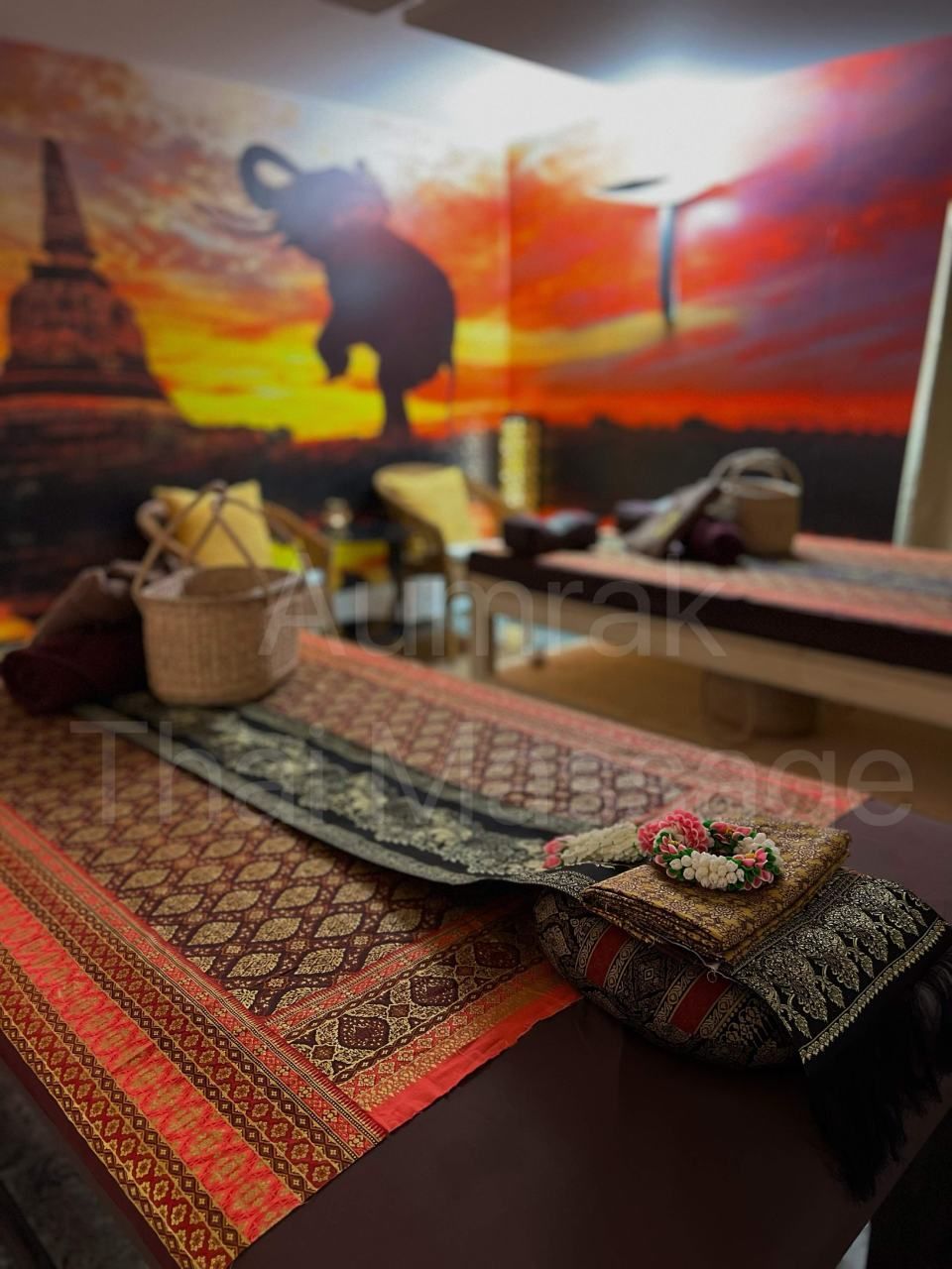 Dekorativ gedeckter Tisch mit gemusterter Tischdecke, Körben und Teeutensilien vor der Kulisse eines Sonnenuntergangs in der Wüste.