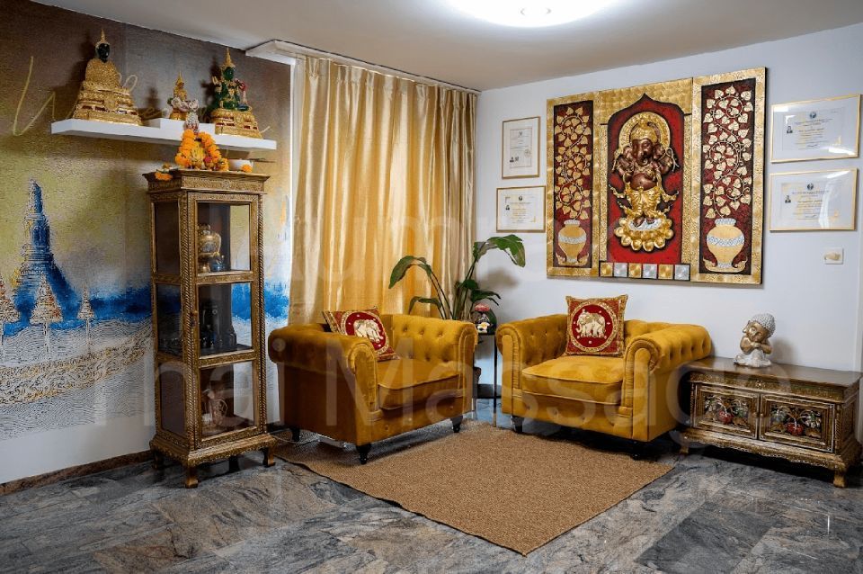 Dekoriertes Wohnzimmer mit goldenen Stühlen, religiösen Wandbildern, einem Glasschrank und warmen Vorhängen.