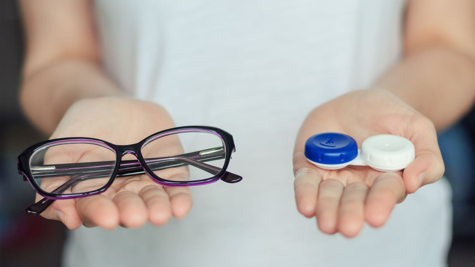 Une paire de lunettes et de lentilles dans chaque main