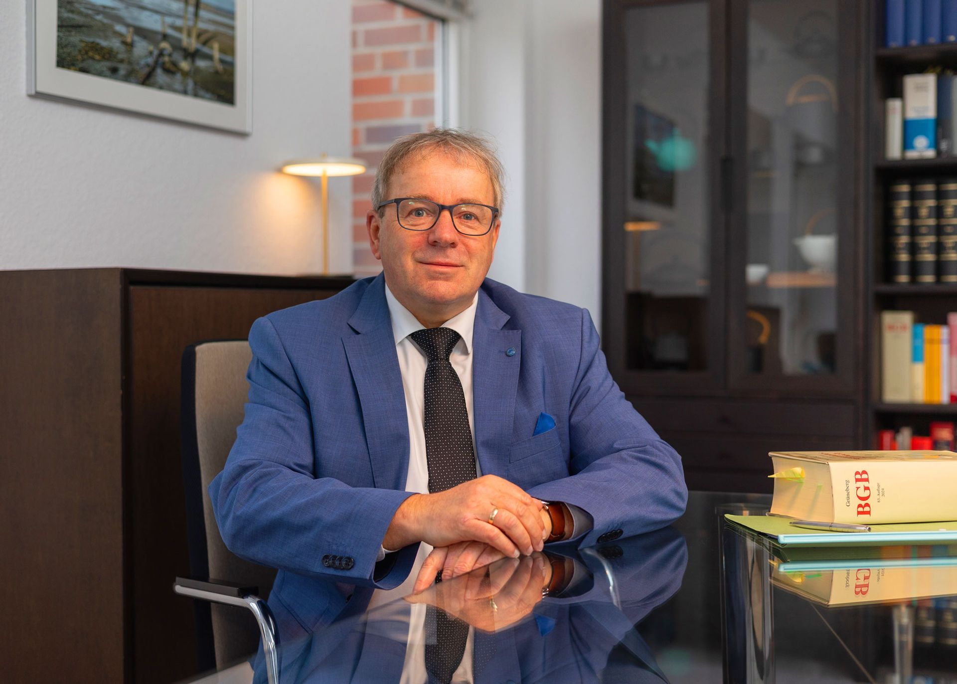 Ein Mann in Anzug und Krawatte sitzt an einem Schreibtisch