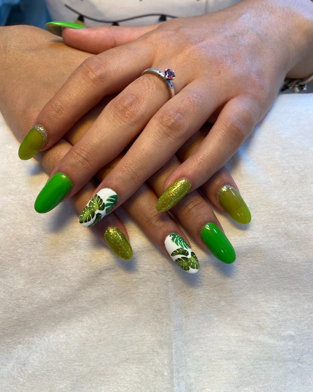 Manos de mujer con uñas verdes y un anillo en el dedo.