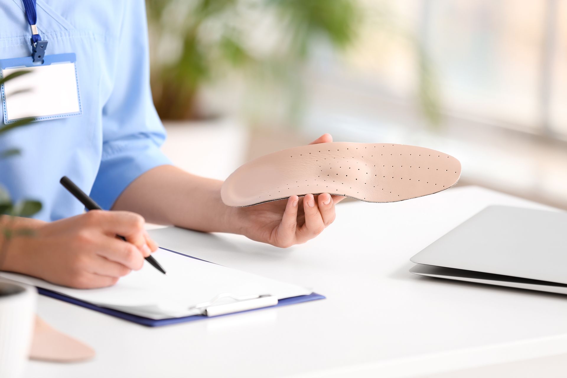 Une professionnelle de santé écrit sur un document et tient une semelle