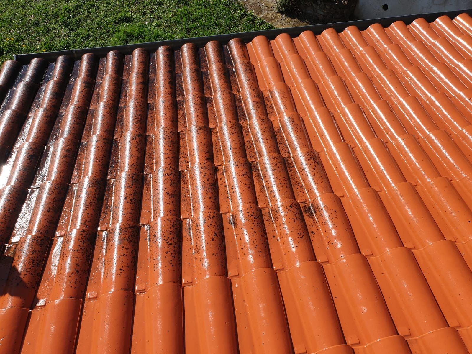 Gros plan sur des tuiles de toit en terre cuite orange avec des taches de mousse sombre ou de saleté.