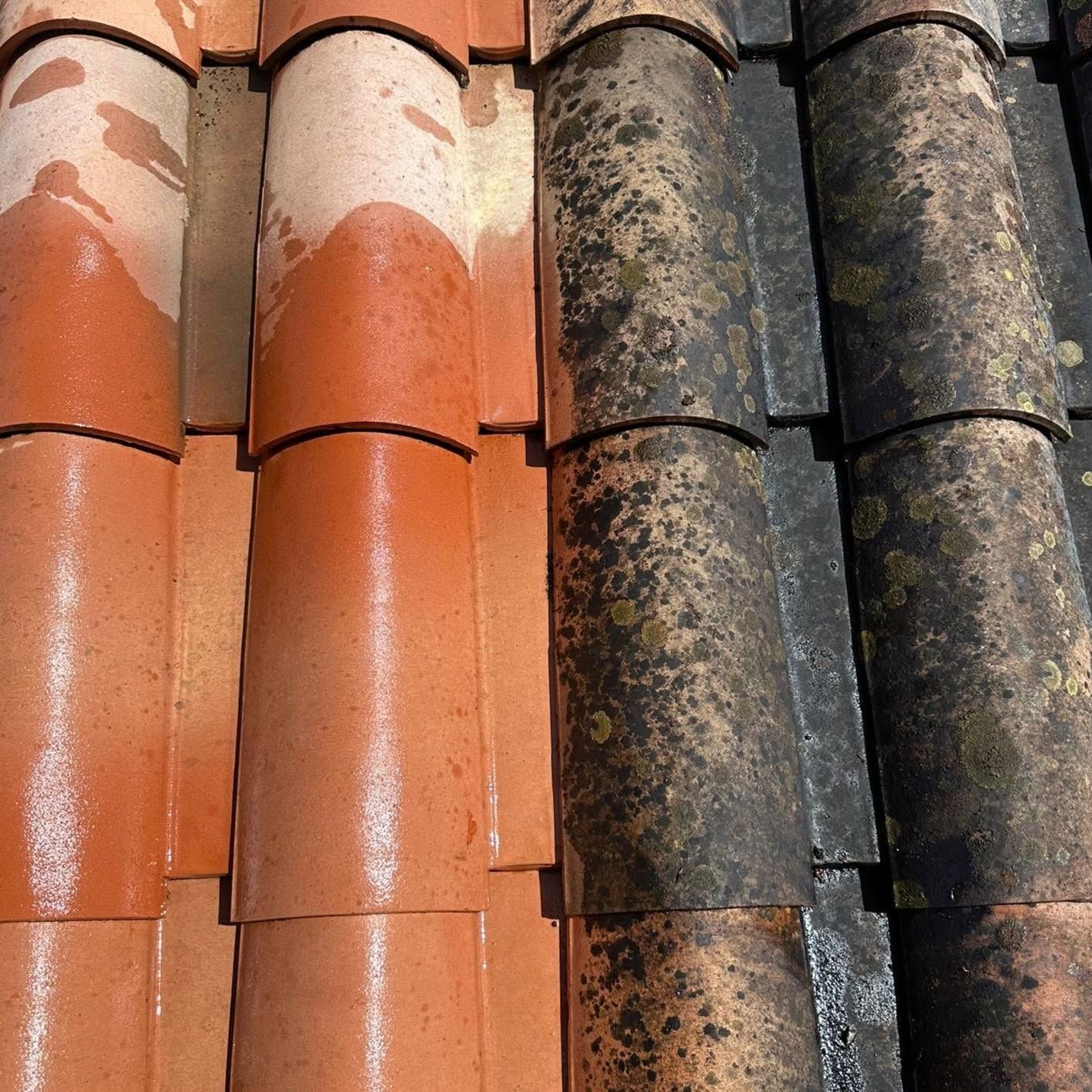 Gros plan sur des tuiles de toit rouges et foncées, usées par le temps, recouvertes de mousse et de saleté.