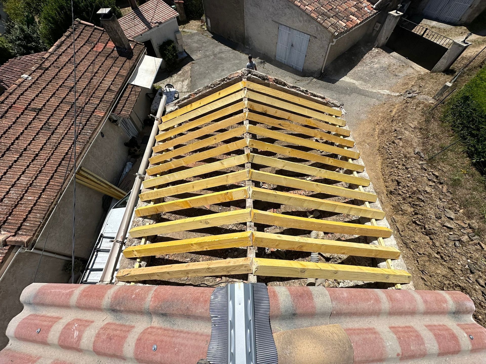 Vue depuis les toits d'un quartier villageois montrant un encadrement de toits jaunes entre des toits de tuiles.