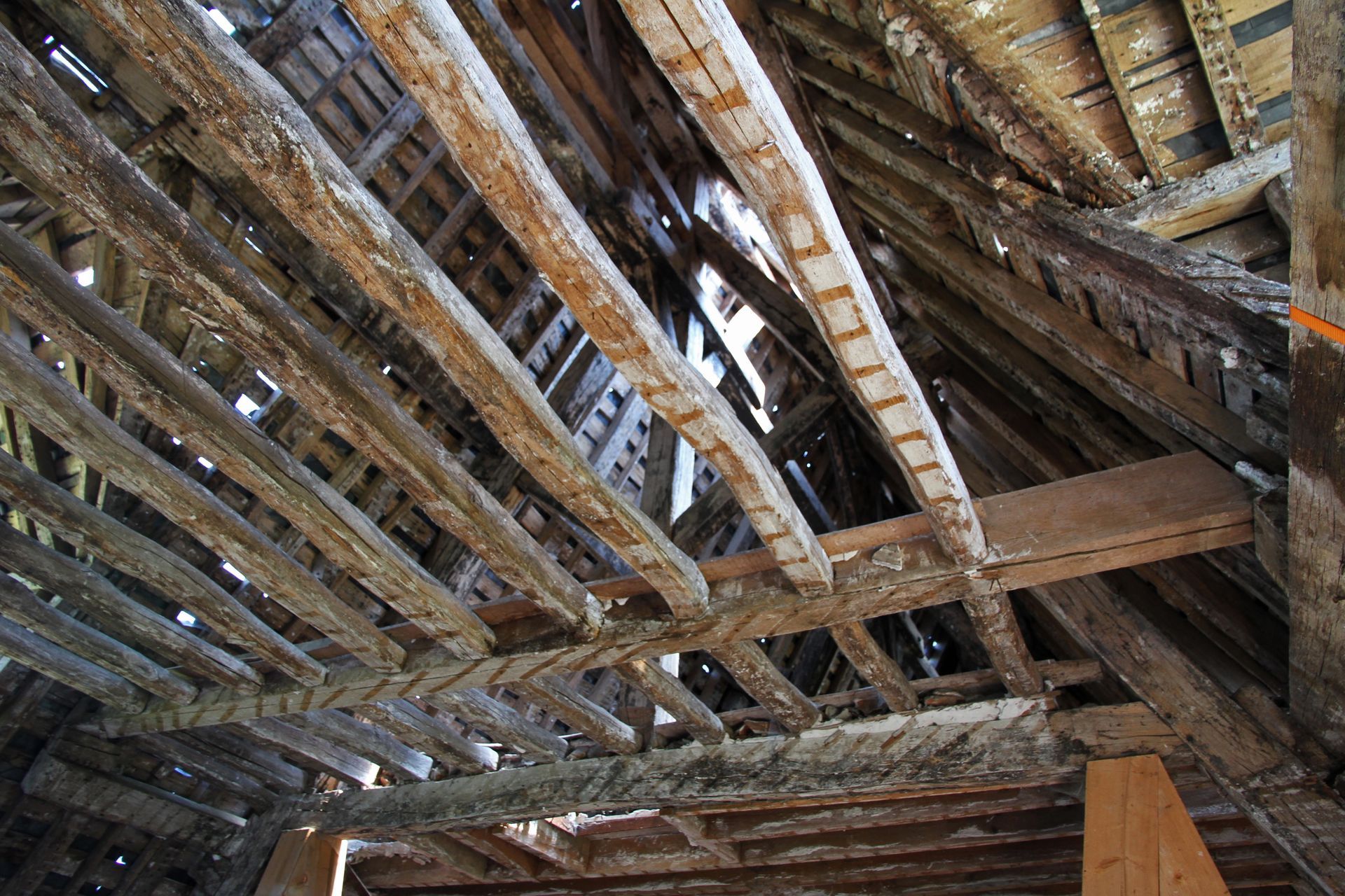 Poutres de toit en bois calcinées et chevrons effondrés à l'intérieur d'un bâtiment