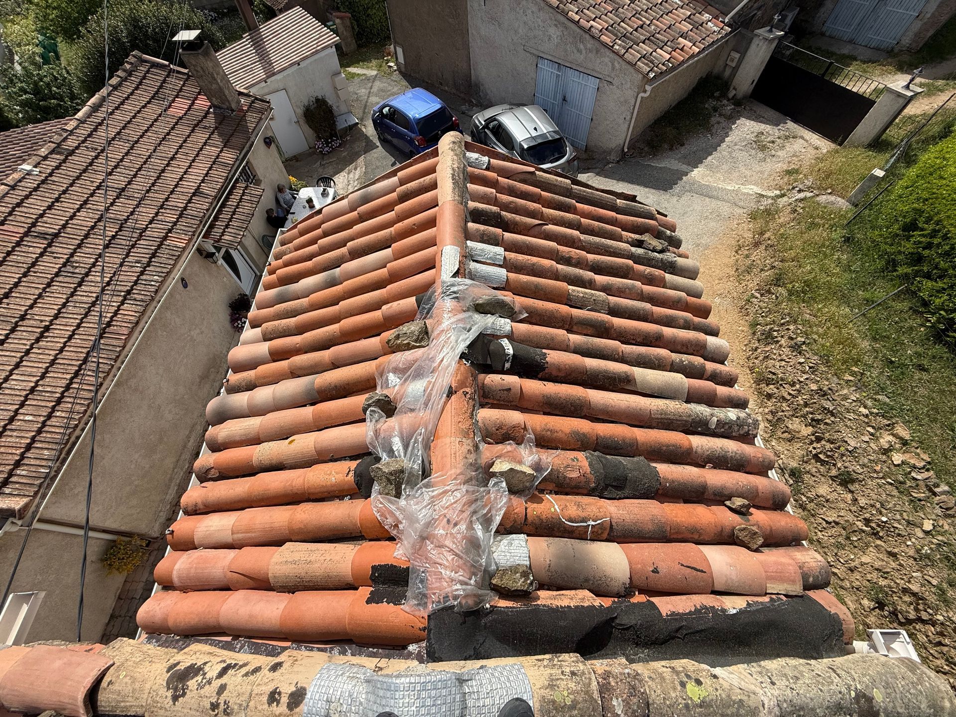 Toiture de tuiles avec une arête centrale en cours de réparation, vue d'en haut dans une cour de village
