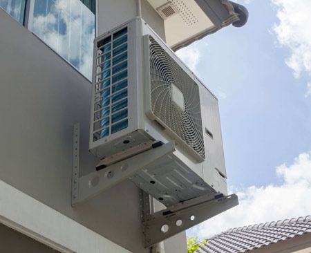 Un acondicionador de aire está montado en el costado de un edificio.