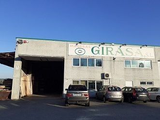 Un edificio con muchos coches aparcados delante.