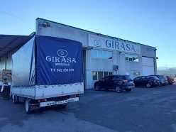 Un camión con una lona azul en la parte trasera está estacionado frente a un edificio.