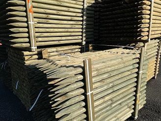 Una pila de postes de madera apilados uno encima del otro.