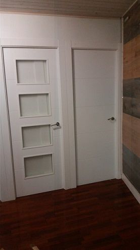 Una habitación con dos puertas blancas y suelo de madera.