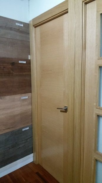 Una puerta de madera está en una habitación al lado de una puerta de vidrio.