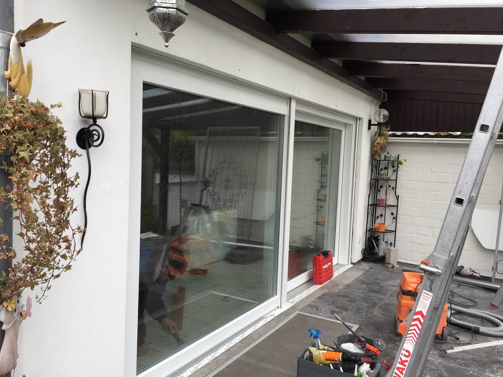 Ein Mann arbeitet an einer Glasschiebetür an einem Haus.