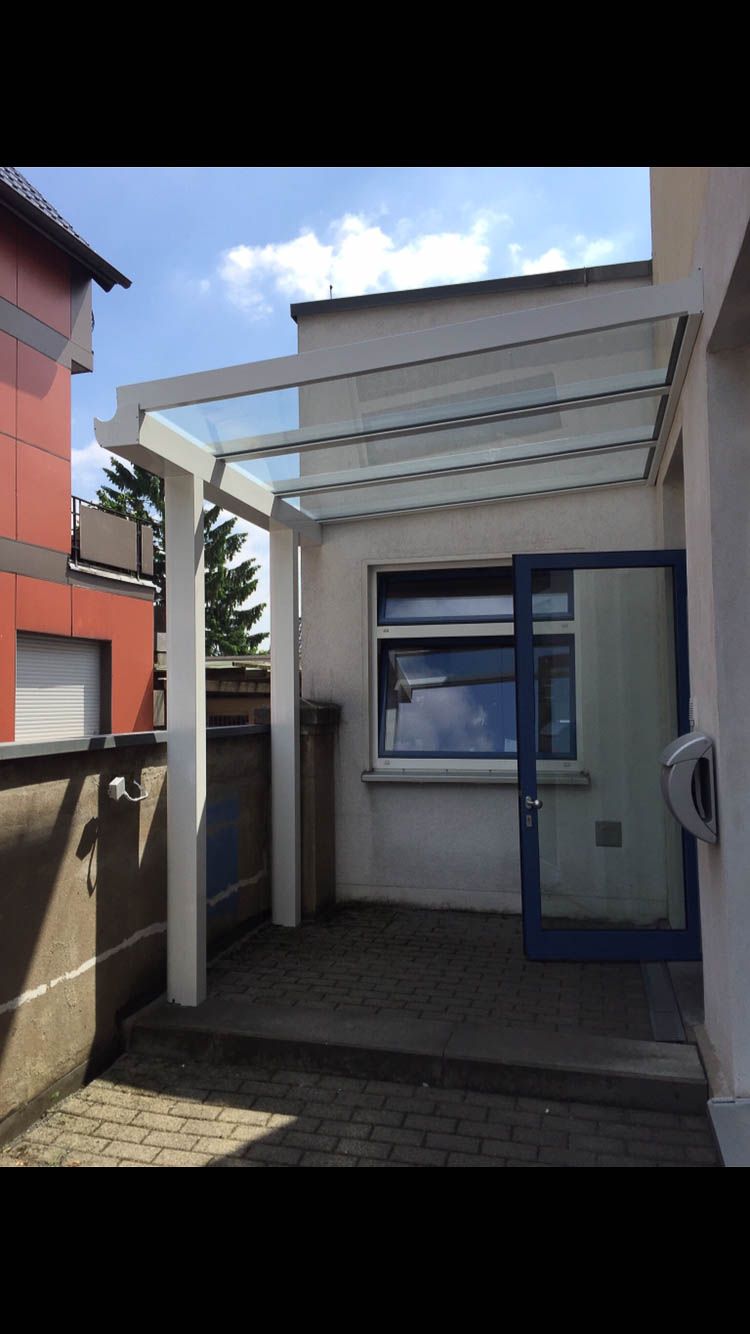 Ein weißes Gebäude mit einer blauen Tür und einem Vordach darüber.