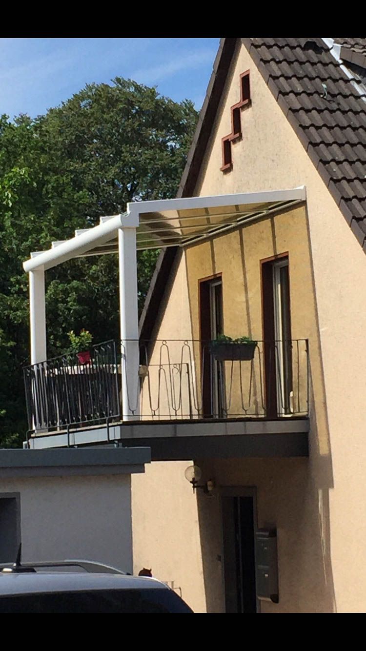 Ein Haus mit einem Balkon und einem davor geparkten Auto.