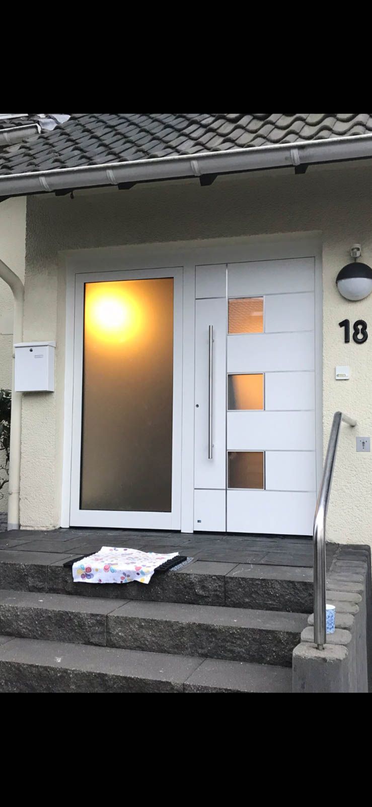 Eine weiße Tür mit Glastür befindet sich oben auf einer Treppe.