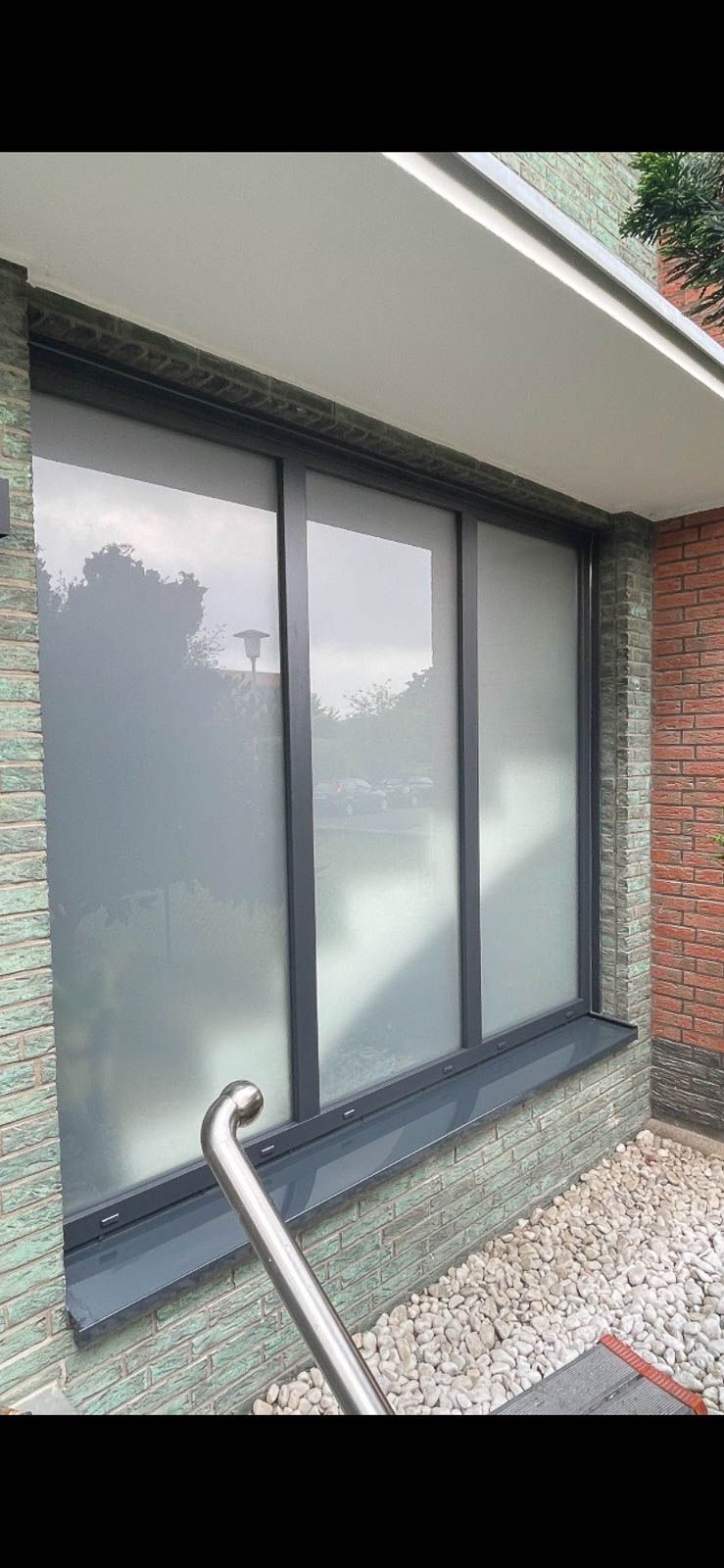 Ein großes Fenster an der Seite eines Gebäudes mit einem Geländer.