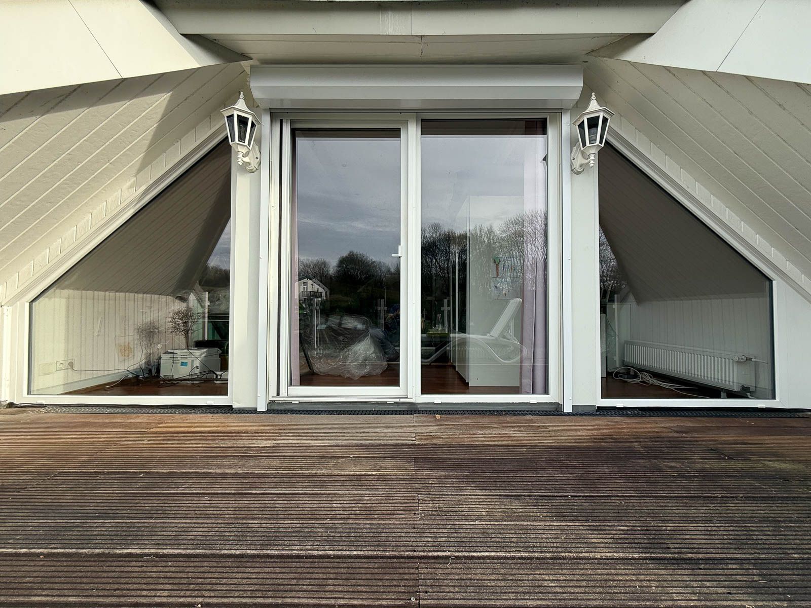 Ein Haus mit einer Holzterrasse und einer Glasschiebetür