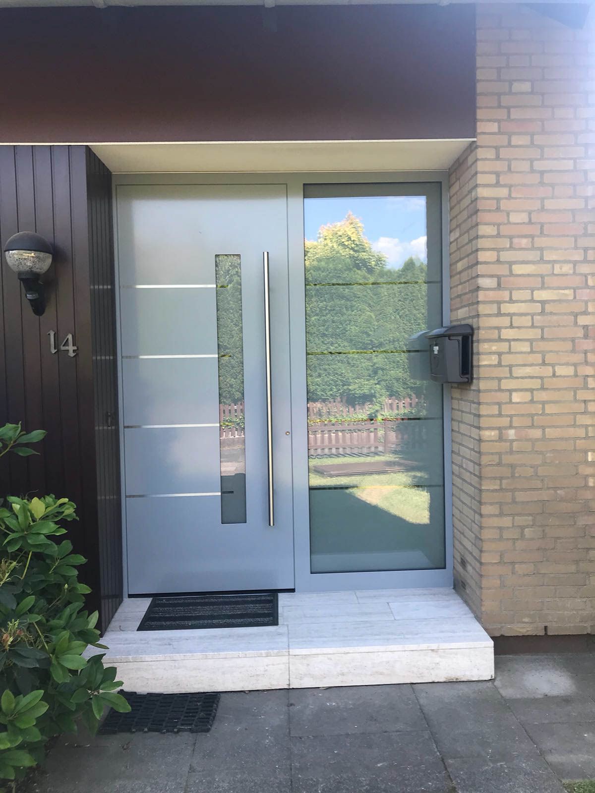 Die Haustür eines Backsteinhauses mit einer grauen Tür