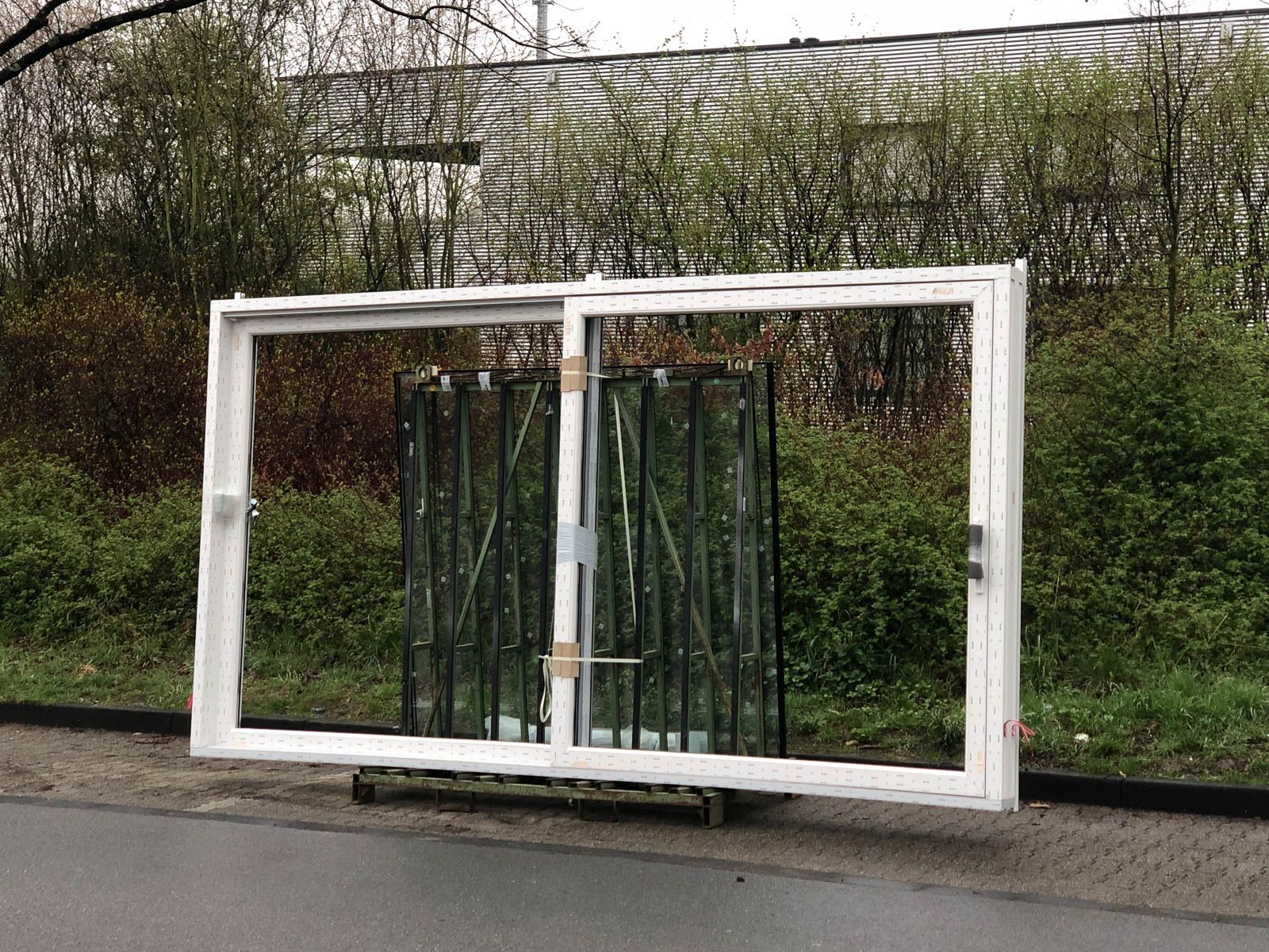 Ein großes Fenster steht auf einer Palette am Straßenrand.