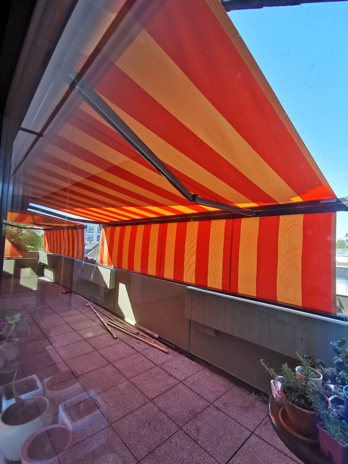 Ein Balkon mit einer rot-gelb gestreiften Markise