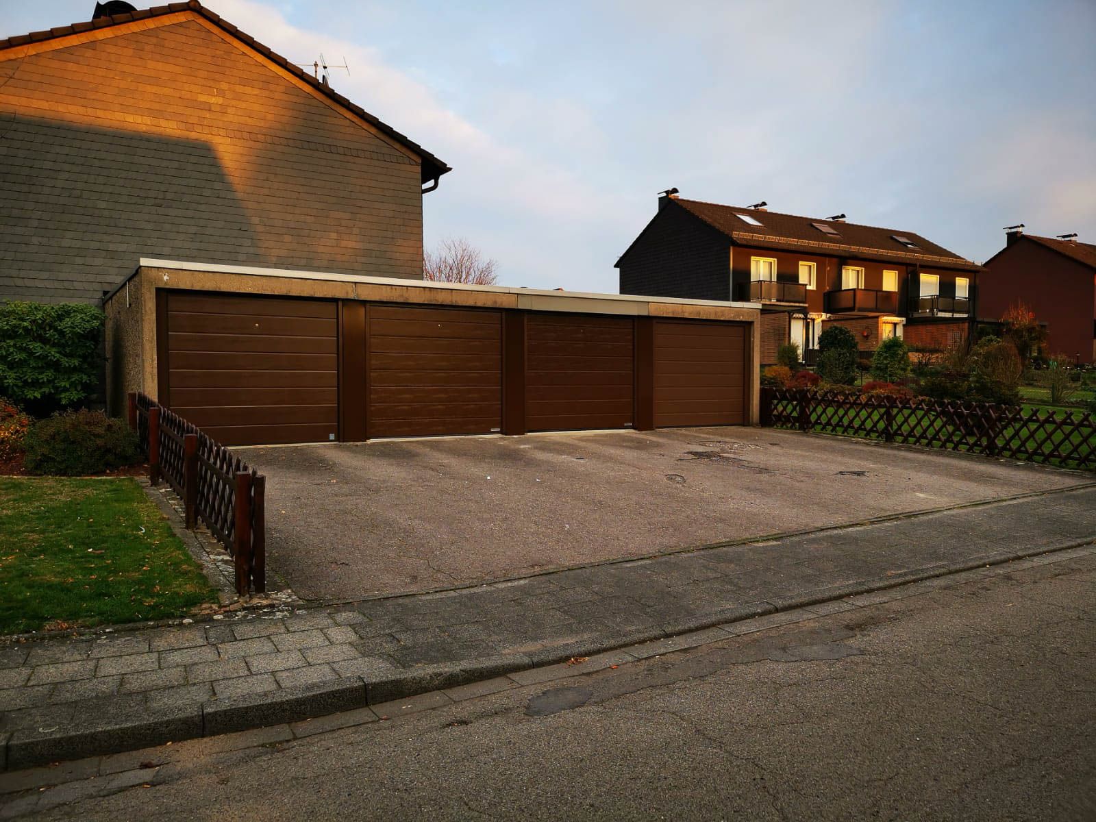 Eine Garage mit drei Türen befindet sich neben einem Backsteingebäude