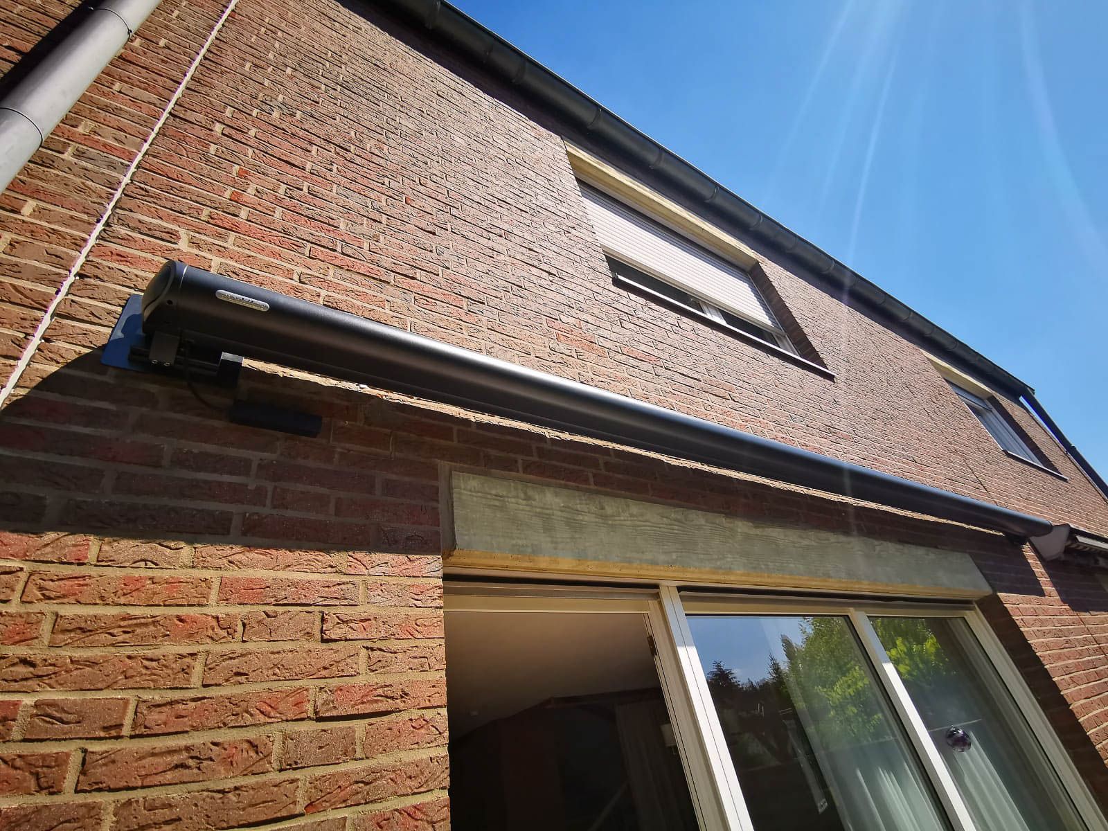 Ein Backsteingebäude mit einer Markise über einer Glasschiebetür.