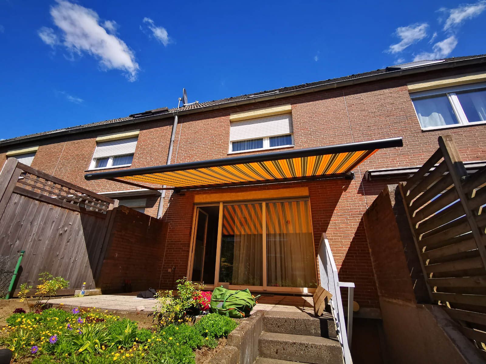 Ein Backsteinhaus mit einer gelben Markise auf der Terrasse