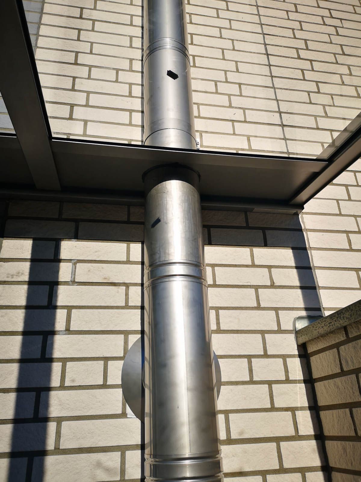 Ein Metallrohr ist an der Seite eines Backsteingebäudes befestigt