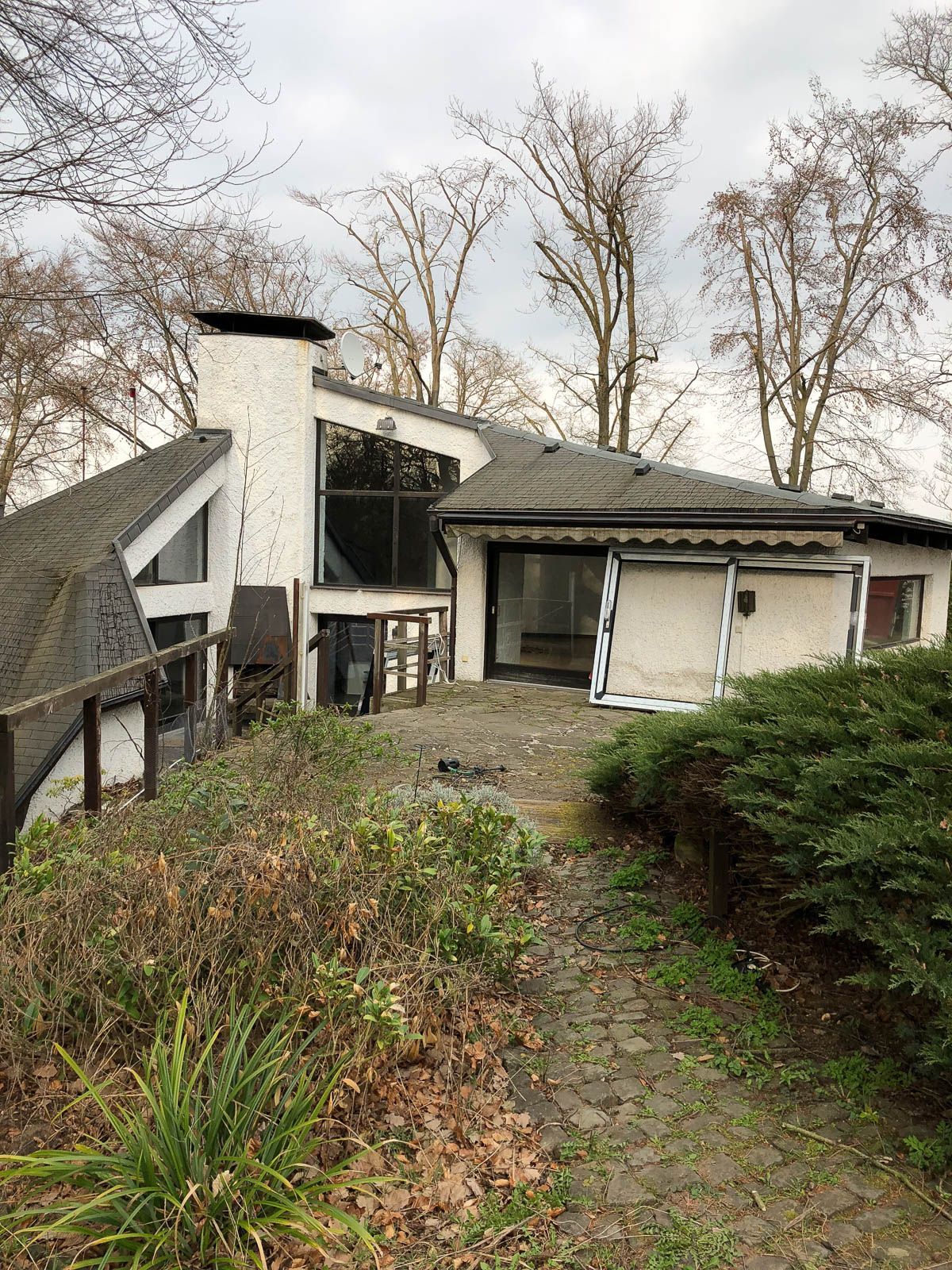 Ein großes weißes Haus mit einem Schornstein auf dem Dach ist von Bäumen umgeben.