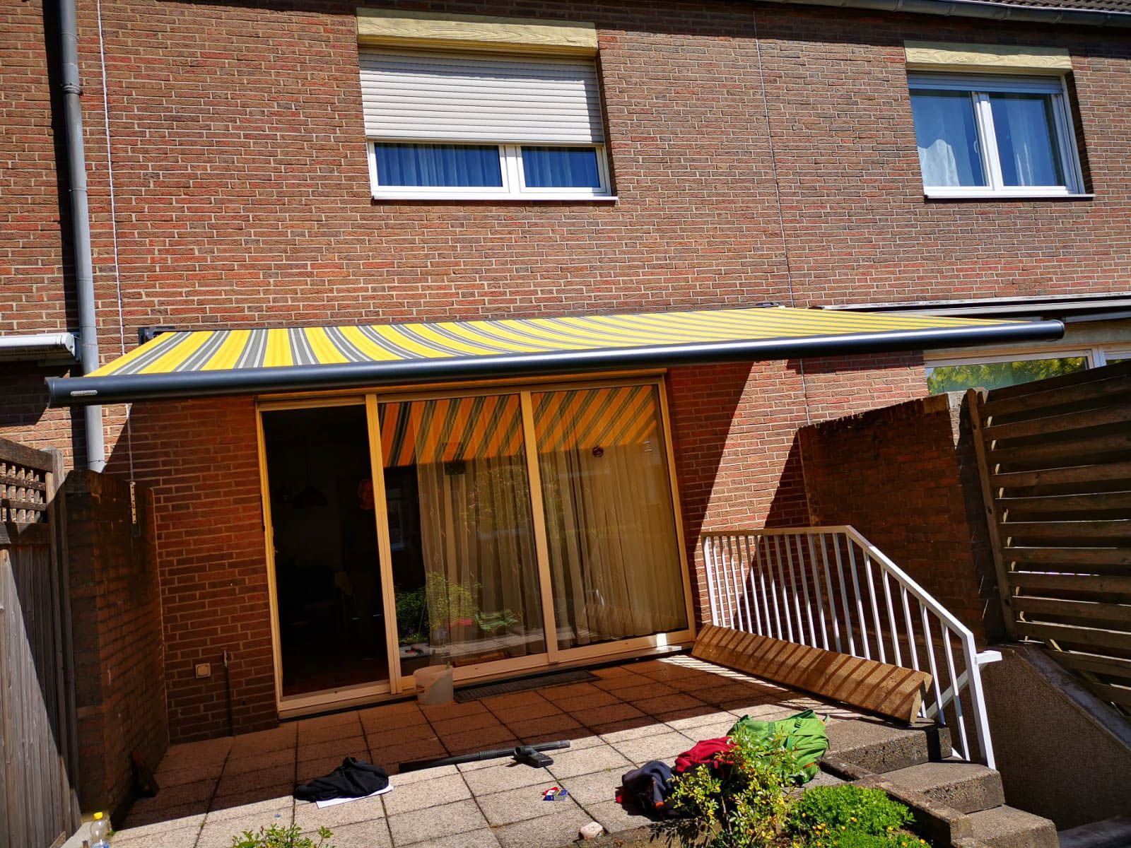 Ein Backsteingebäude mit einer gelben Markise über einer Terrasse.