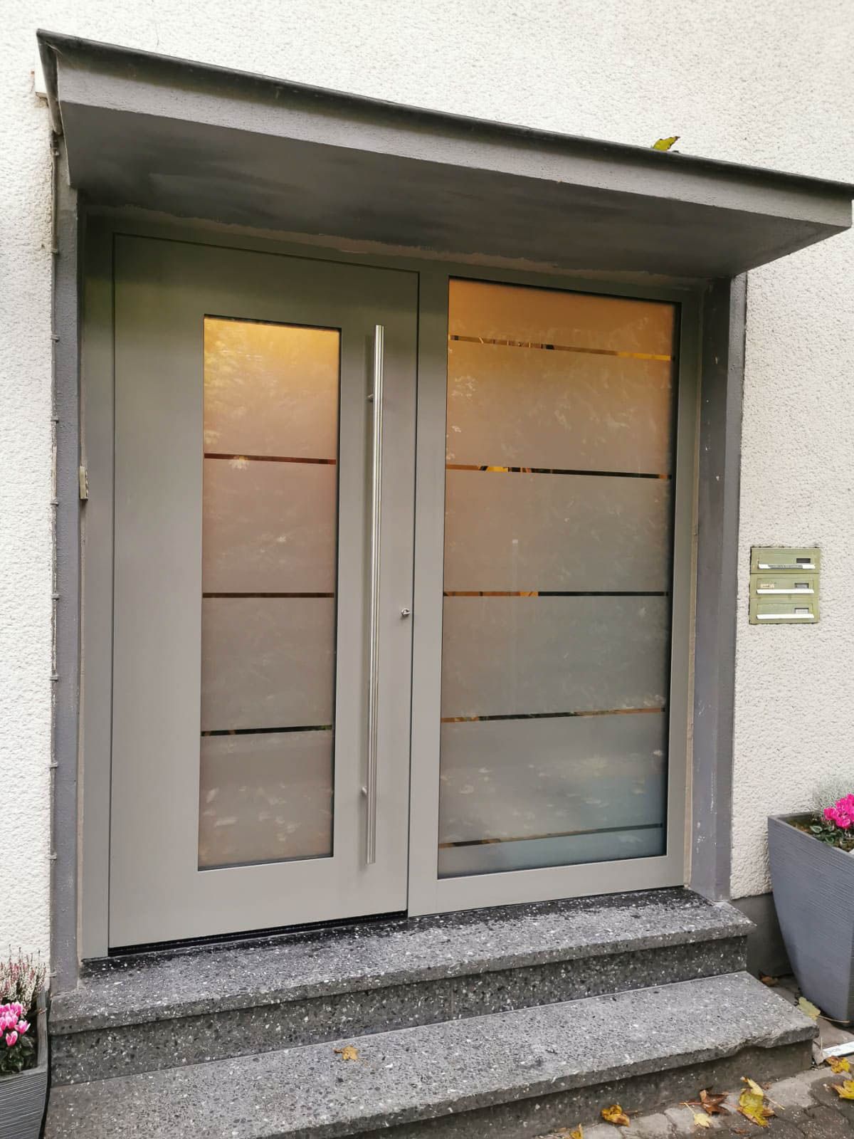 Eine Vordertür mit einem Vordach darüber und Stufen, die dorthin führen.